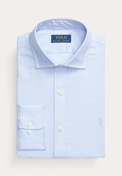 Camisa azul clara com botões, com um pequeno logótipo bordado no peito, um colarinho clássico e mangas longas com punhos abotoados.