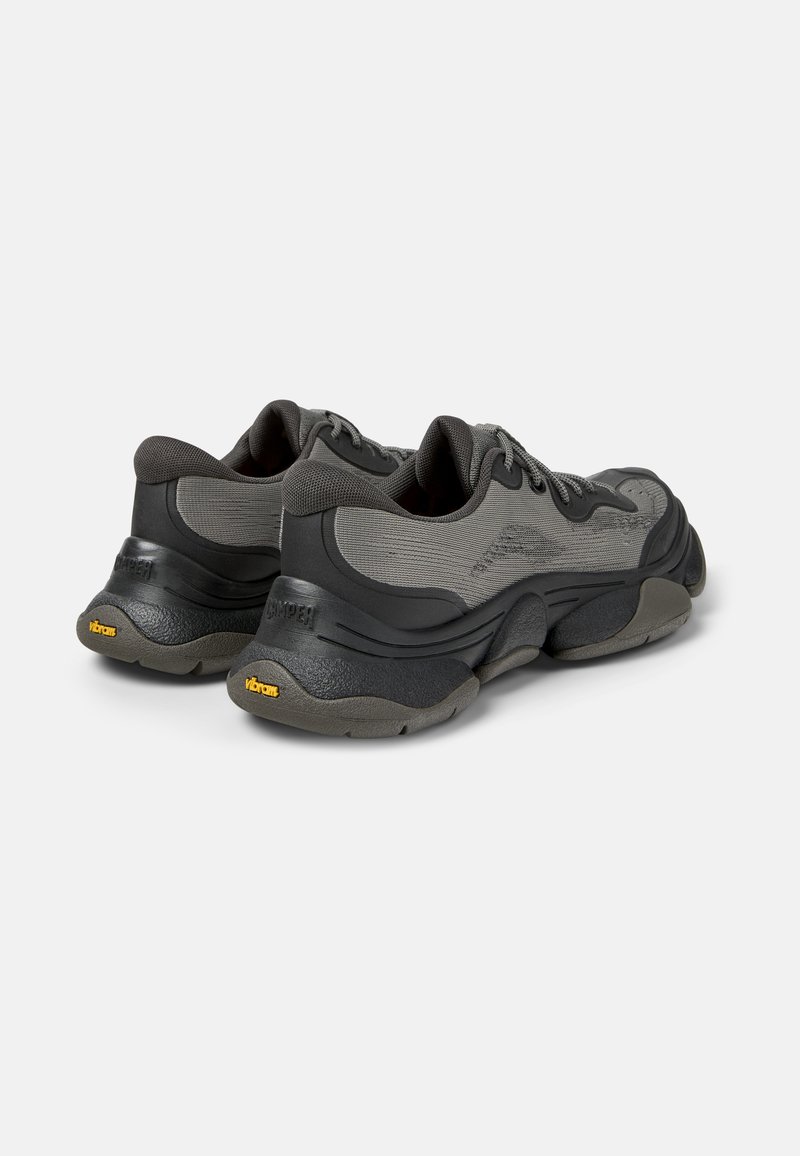 Graue Sportschuhe mit texturiertem Obermaterial, gepolstertem Schuhkragen und dicken Vibram-Sohlen. Zu den Merkmalen gehören Schnürsenkel und verstärkter Fersenhalt.