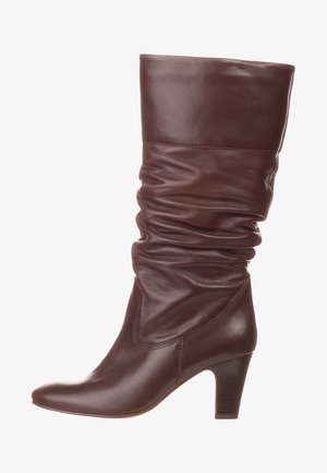 Botín de cuero burdeos con diseño holgado, punta afilada y tacón moderado; textura suave con sutiles detalles de costura.