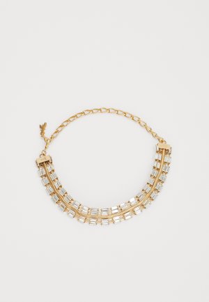 Kultainen rannekoru, jossa on kaksi riviä suorakaiteen muotoisia kirkkaita kristalleja ja säädettävä lukko valkoisella taustalla.