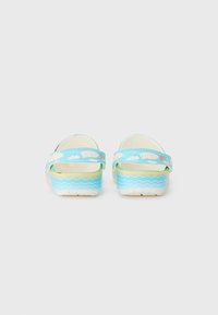 Blaue Kunststoff-Clogs mit gelbem Innenfutter, Wellenmuster in der Sohle und zwei Wolkenmotiven auf dem Riemen. Leichtes Design, offener Rücken.