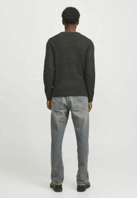Maglione in maglia waffle khaki con collo rotondo, indossato con jeans grigi chiari a vestibilità comoda e scarpe nere, visto da dietro.