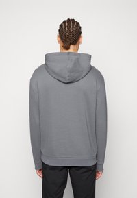 Felpa grigia con cappuccio regolabile, polsini a coste e una vestibilità leggermente rilassata. Tessuto dalla superficie liscia, design semplice e senza loghi visibili.