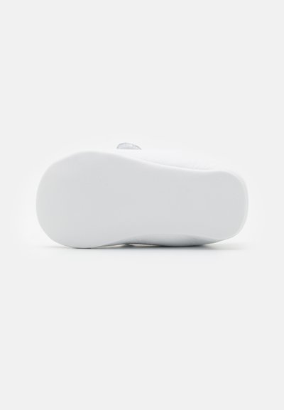 Hvit såle med teksturert overflate, flat design og lett buet kant. Glatt finish med minimale detaljer og ingen synlig merking.