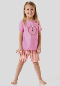 T-shirt rose clair avec un design de symbole de paix, associé à un short rayé multicolore dans des teintes de rose, orange et jaune.