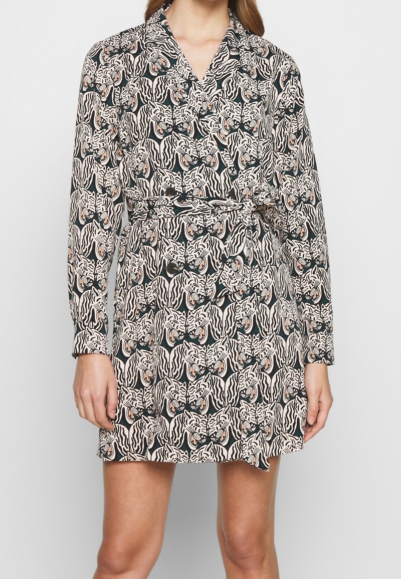 Mini-robe ceinturée à manches longues avec un motif visage de tigre noir et blanc sur fond foncé.