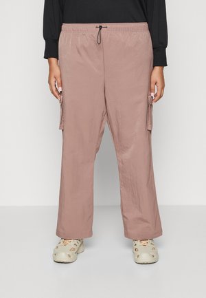Pantalons cargo légers de couleur rose clair, avec une taille élastique, une fermeture à cordon et des poches latérales. Portés avec des chaussures beiges perforées.