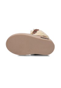 Bruine en crèmekleurige pantoffel met een gewatteerde, pluche bovenkant en een stevige, geribbelde tan buitenzool met een cirkelvormig logo en maatmarkering.