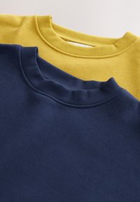 Dva duksa su slojevita, jedan žuti i jedan mornarsko plavi. Oba imaju rebraste okrugle izreze za vrat i meke teksture.