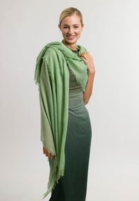 Hele roheliselt sallilt, mis on valmistatud pehmest ja voolavast materjalist ning millel on konksudega servad. Elegantselt tumerohelise kleidi kohal, luues kihilise efekti.