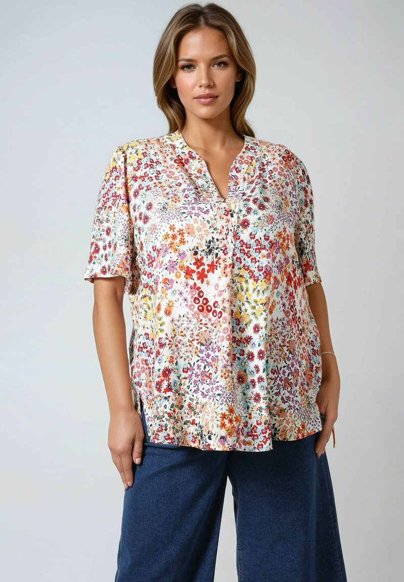 Flower-patterned short-sleeve shirt in light fabric, featuring a V-neck and side slits. The design includes multicolored floral prints against a cream background.