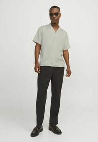 Short-sleeve, light gray shirt with a collar, paired with black trousers and black shoes. Smooth fabric with a relaxed fit and button closure.