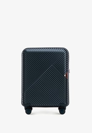 Valise rigide avec texture à rayures diagonales, couleur bleu marine, accents en rose doré, et quatre roues roulantes pour la maniabilité.