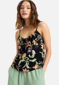 Top de tirantes negro con estampados tropicales multicolores, tirantes delgados y un frente fruncido. Combinado con pantalones sueltos verdes claros.