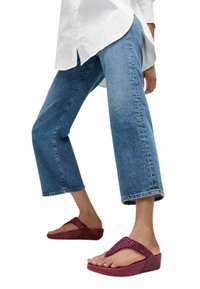 Maroonen sleehakken met een gestructureerde band versierd met strass-steentjes, gecombineerd met cropped blauwe spijkerbroeken en een oversized wit overhemd.