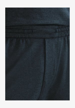 Tamne sive trenirke s elastikom u struku i vezicom. Glatka tekstura s bočnim džepovima i suptilnim meliranim uzorkom.