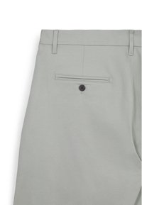 Helle graue Hose mit glatter Textur, ausgestattet mit einer Gesäßtasche, die mit einem dunklen Knopf gesichert ist, sowie Gürtelschlaufen entlang des Bunds.