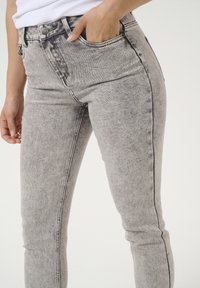 Svijetlosive skinny traperice od denima s izblijedjelom teksturom, s medijem strukom, prednjim džepovima i kontrastnim šavovima.