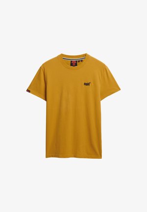 T-shirt à manches courtes en coton jaune moutarde, avec un petit logo noir sur la poitrine gauche et une étiquette d'accent rouge sur la manche gauche.