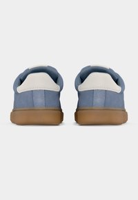 Μπλε σουέντ αθλητικά παπούτσια με λευκό ταμπελάκι στη φτέρνα και ταμπά λαστιχένια σόλα. Στρογγυλεμένο σχήμα, επενδεδυμένος γιακάς και μινιμαλιστικός σχεδιασμός.