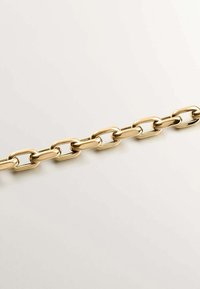 Collar de cadena de color dorado hecho de eslabones de metal, que presenta formas ovaladas con una superficie pulida y lisa, alternando tamaños de eslabones.