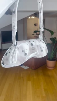 Bijela torbica s sjajnim završetkom s prikazima polarnih medvjeda. Prozirne trake pričvršćene su na zakrivljeno tijelo. Jednostavno zatvaranje na gumb.