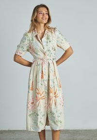 Abito in lino ricamato floreale con maniche corte, chiusura a bottoni e vita svasata; presenta cuciture multicolori in rosa e verde.