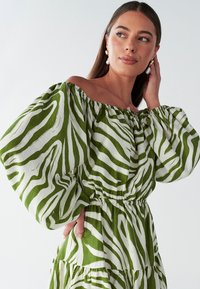 Roheline ja valge õlgadest avatud kleit puffvarrukatega, millel on sebratriibu muster, elastne vöökoht ja kihiline volangiline äär.