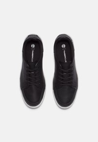 Zwarte leren sneakers met een gladde textuur, voorzien van zwarte veters, witte rubberen zolen en een logo op de binnenzool. Bovenaanzicht.