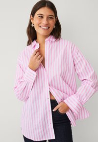 Chemise à rayures roses et blanches avec boutons, col, manches longues et détails aux poignets, confectionnée dans un tissu léger avec une coupe décontractée.