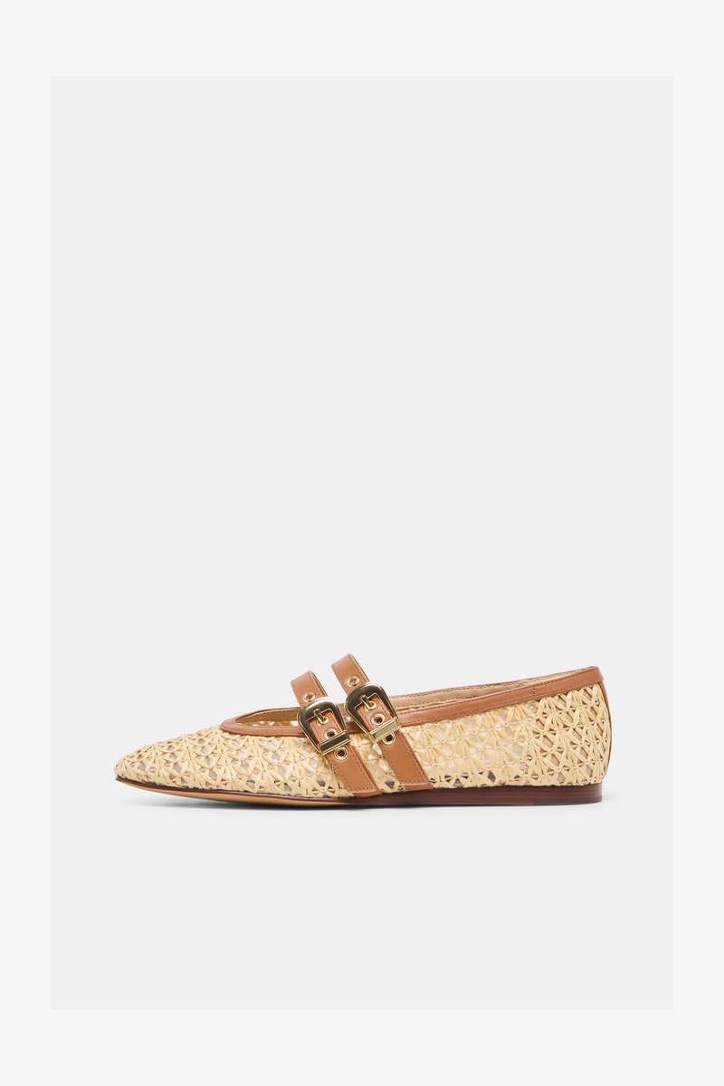 Teräväkärkinen beige kudottu tasapohjainen kenkä, jossa kaksi ruskeaa nahkahihnaa ja kullansävyiset soljet valkoisella taustalla.
