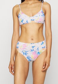 Conjunto de biquíni com padrão floral, apresentando um decote em V, alças ajustáveis e parte de baixo de cintura alta. As cores incluem rosa claro, azul e amarelo.