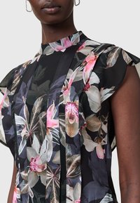Schwarz-bluse mit floralen Mustern, die kurze Rüschensleeves, einen hohen Kragen und eine Mischung aus rosa und grünen botanischen Drucken aufweist.
