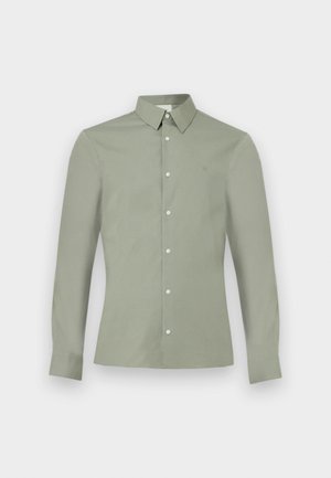 Camisa de manga larga verde claro con cuello abotonado y botones blancos, mostrada sobre un fondo blanco liso.