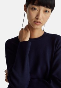 Granatowy prążkowany sweter z okrągłym dekoltem i długimi rękawami, o luźnym kroju i miękkiej fakturze.