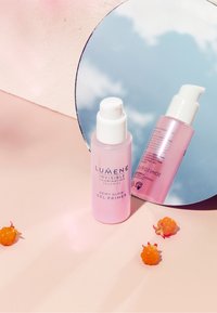 Lumene Dewy Glow Gel Primer in a transparent pink bottle with a white pump; features reflective surface and soft, round shape.