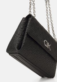 Borsa nera con un motivo a logo testurizzato, minuteria in argento e tracolla a catena, dalla forma strutturata e chiusura a pattina.