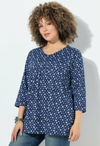 Tunika blu navy con un motivo geometrico bianco e azzurro, scollo rotondo, maniche 3/4 e vestibilità rilassata.