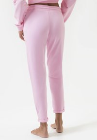 Lichtroze sweatpants van zacht materiaal, met een elastische tailleband, omgeslagen boorden en een relaxte pasvorm. Geen zichtbare logo's of patronen.