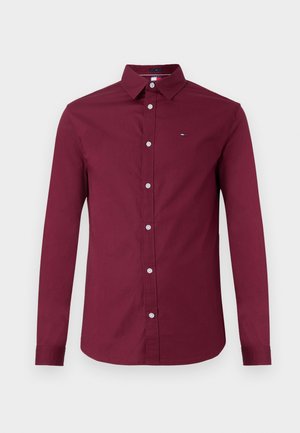 Burgundy long-sleeve shirt made of cotton, featuring a pointed collar, front button closure, and a small logo on the chest.