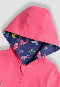 Fény rózsaszín, cipzáras kapucnis pulóver, a kapucni belsejében tengerész kék dinoszaurusz mintával. Puha pamut anyag, egyszerű dizájn és laza szabás.