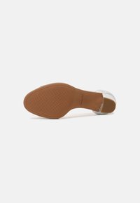 Semelle d'une chaussure plate marron avec une semelle texturée et un petit talon, nom de marque « Clarks » visible près de la zone du talon.