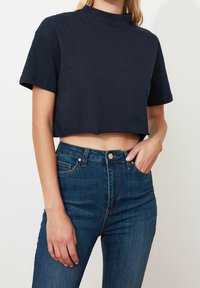 Marinblå croppad t-shirt i bomull med hög hals och korta ärmar, tillsammans med högmidjade blå denimjeans.