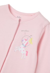 Top de algodón de color rosa claro con un unicornio impreso en un traje espacial, con lunares y una luna. El diseño incluye el texto "sueño espacial."