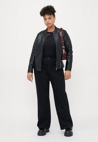 Black faux leather jacket, fitted at the waist, paired with black leopard print wide-leg pants. Black platform shoes and a brown crossbody bag.
