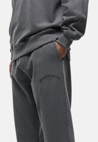 Grijze sweatshirt en bijpassende sportbroek van katoenmix, met ribgebreide boorden en een bedrukte logo-detail op de broek.