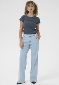 Dark grey ribbed short-sleeve top paired with light blue wide-leg jeans. The outfit is complemented by black pointed-toe heels.