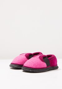 Roze en donkerroze vilt slippers met zwarte elastische banden, ronde vorm en een gestructureerd oppervlak. Bevat een gestikte rand en een rubberen zool.