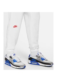 Nike Air Max 90-sneakers har grå, svart och blå färgblock, nät- och mockamaterial, runda snörning och en synlig luftkuddsenhet.