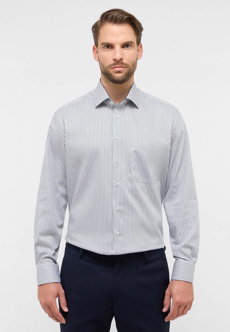 Camicia a righe bianca e blu navy, con colletto button-down, maniche lunghe e una tasca sul petto, dal tessuto complessivamente liscio.